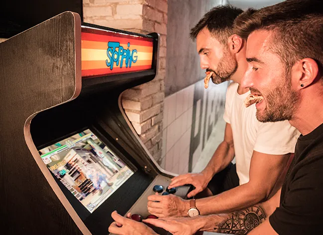 Clientes jugando a la máquina recreativa de Porco Dio