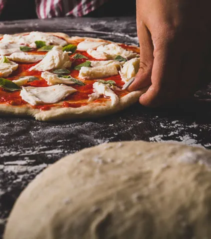 Masa de pizza estirada a mano con tomate y mozzarella