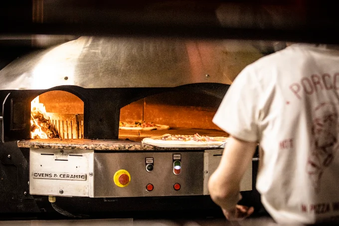 Pizzero de Porco Dio metiendo una pizza en el horno