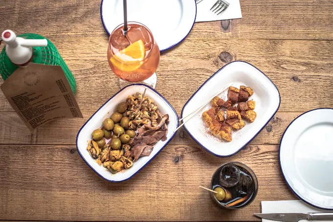 Vermut y tapas en una mesa de Porco Dio